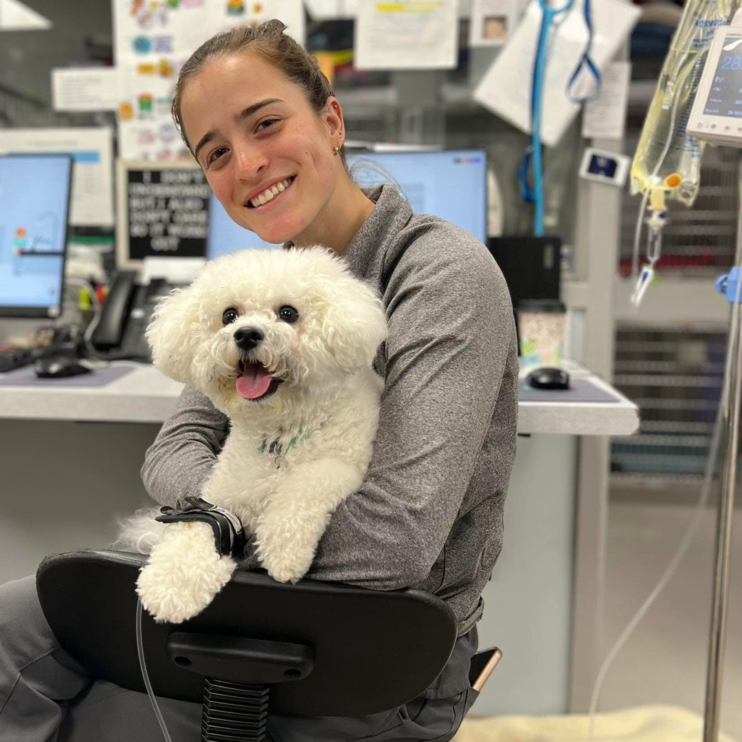 Woman Smiling And sitting in a chair while Holding Small White Dog